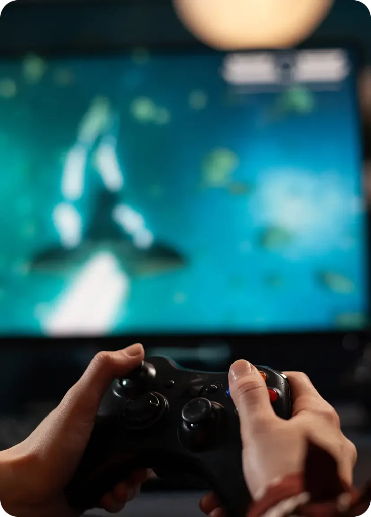 Ręce gracza trzymają gamepada podczas gry na ekranie